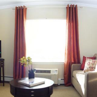 A cozy living room with red curtains, a sofa, and a coffee table in front of a window.