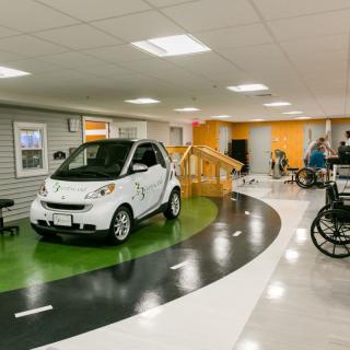 An indoor rehabilitation center featuring a car and wheelchair training area.