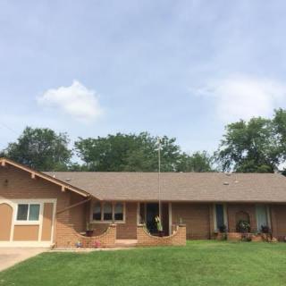 A single-story suburban house with a well-maintained lawn and clear sky.