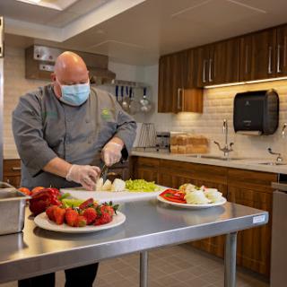 A chef in a professional kitchen prepares fresh ingredients while following safety protocols.