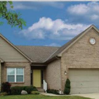 A suburban house with a brick exterior and attached garage under a cloudy sky.
