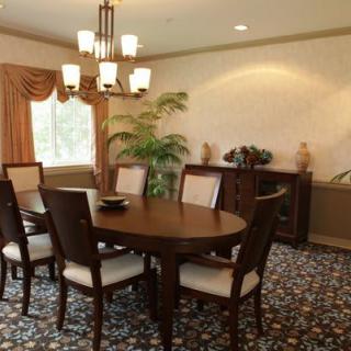 A cozy dining room with a wooden table and chairs, illuminated by a chandelier.