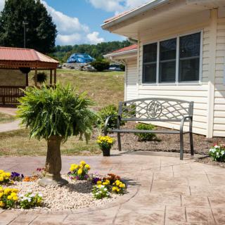 A quaint garden patio with a bench and colorful flowers.