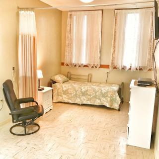 A cozy bedroom with a single bed, nightstand, and chair.
