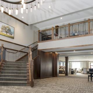 Spacious lobby area with a grand staircase and elegant chandelier.