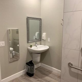 A clean and modern bathroom with a sink, mirror, hand dryer, and waste bin.