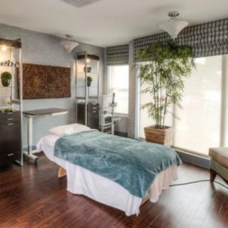 A tranquil massage room with a bed, soft lighting, and plants for a relaxing atmosphere.