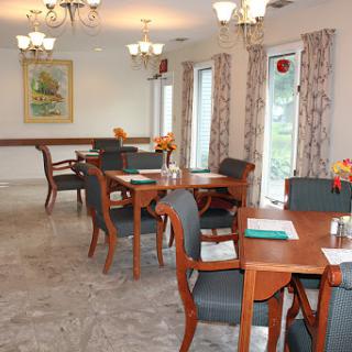 A well-lit dining room featuring wooden tables and chairs, adorned with floral decorations and elegant chandeliers.