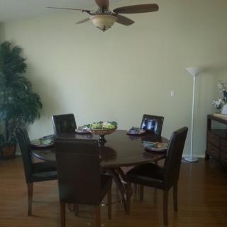 A dining room setup with a circular table and chairs, featuring a ceiling fan and indoor plant.