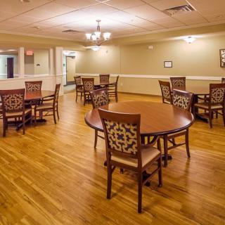 An empty dining room with wooden tables and chairs arranged neatly on a hardwood floor.