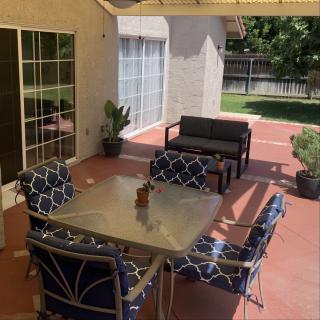 A cozy patio setting with a table, chairs, and a sofa under a shaded area in the backyard.