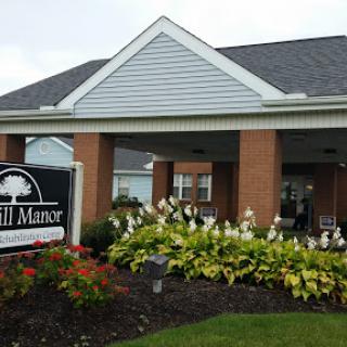 The entrance to Hill Manor, surrounded by lush floral landscaping.