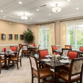 An elegantly designed dining room with neatly arranged tables and chairs, soft lighting, and large windows.