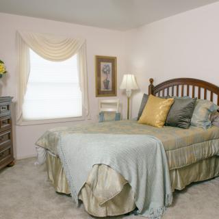 A cozy bedroom with a neatly made bed and a window letting in natural light.