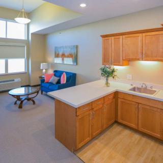 A modern apartment with an open floor plan featuring a cozy living room and a compact kitchen.