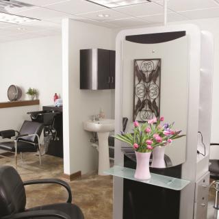 A modern hair salon interior with a decorative mirror, chairs, and fresh flowers.