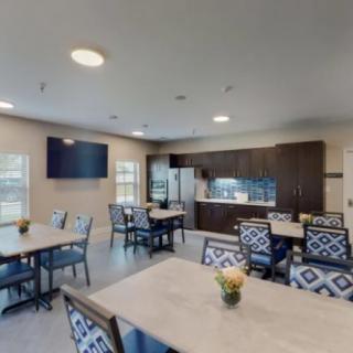 A modern dining area with tables, chairs, and a kitchen setup.