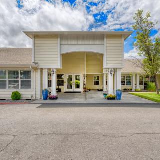 A modern building entrance with a wide driveway and a partly cloudy sky.