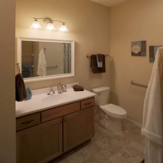 A neatly organized bathroom with a vanity, mirror, and well-placed lighting.