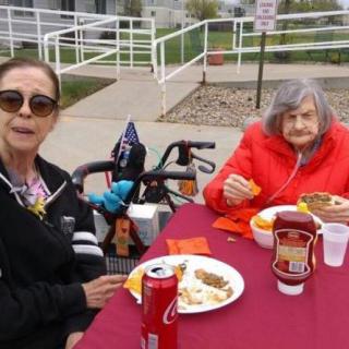 Two elderly women enjoying an outdoor meal together.