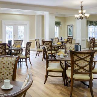 A cozy dining area with elegant chairs and tables, adorned by a chandelier.