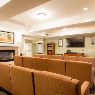 A cozy living room with sofas facing a television and a fireplace.