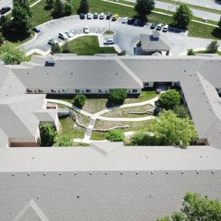 Aerial view of a building complex with a central courtyard featuring pathways and greenery.