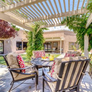 A cozy outdoor patio with a pergola and comfortable seating surrounded by lush greenery.