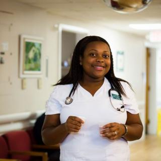 A nurse in a hospital corridor wearing a uniform.