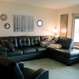 A cozy living room featuring a leather sectional sofa, wall art, and warm lighting.