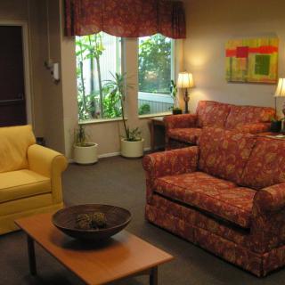 A cozy living room featuring a floral sofa, a yellow armchair, a wooden coffee table with a decorative bowl, and soft lighting from lamps.