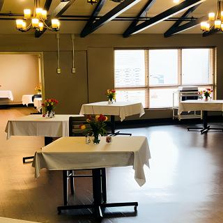 A spacious dining room with elegantly set tables and chandeliers.