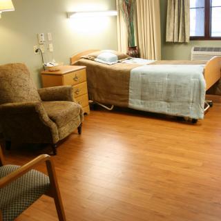A hospital room with a single bed, chairs, and other furniture.