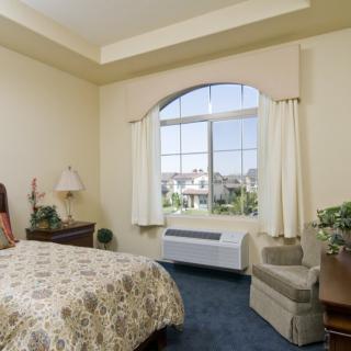 A cozy bedroom with a patterned bedspread and a large window overlooking the outdoors.