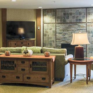 A cozy living room with a sofa, television, and decorative elements including a lamp and tables.