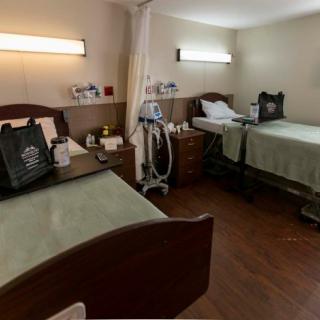 A hospital room with two beds, each accompanied by medical equipment and bedside tables.