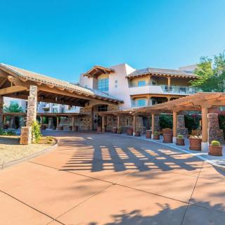 A sunny view of a resort entrance with rustic architecture.