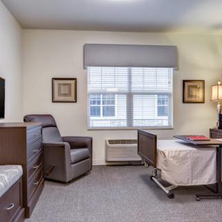 A well-furnished bedroom with a chair, bed, and window.