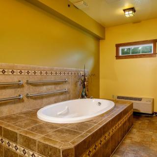 A bathroom with a tiled bathtub and yellow walls.