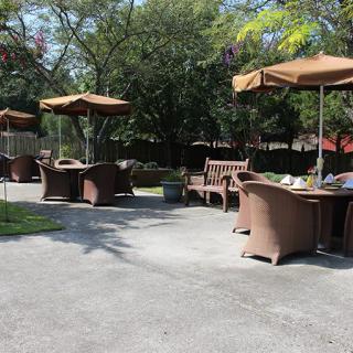 An outdoor patio area with tables, chairs, and umbrellas under a sunny sky.