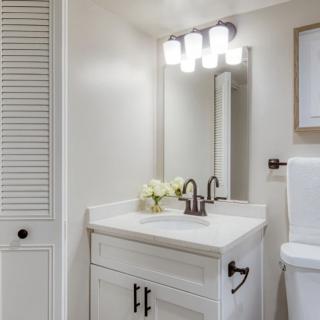 A modern bathroom with a white vanity and bright lighting.