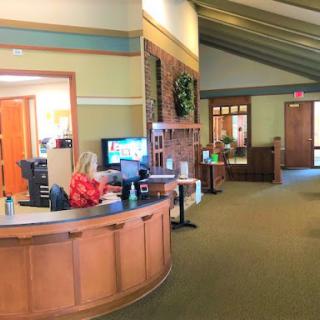 A welcoming reception area with wooden furniture and green walls, featuring a cozy atmosphere.