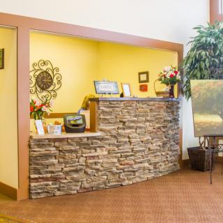 A cozy reception area featuring a stone-designed desk, decorative elements, and seating.
