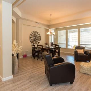 A modern and cozy living room with a dining area, featuring dark furniture and abundant natural light.
