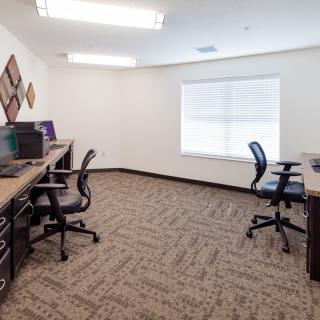 A modern office workspace with multiple desks and chairs arranged neatly.