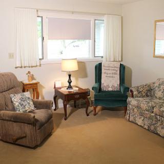 A cozy living room featuring a recliner, sofa, and a lamp next to a window.