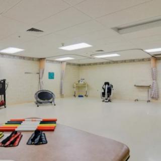 A spacious rehabilitation room equipped with exercise machines and therapy tools.