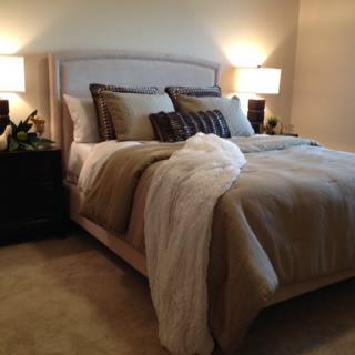 A cozy bedroom with a neatly made bed, flanked by nightstands and illuminated by two lamps.