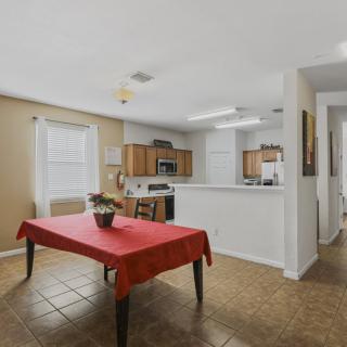 An open-layout kitchen and dining area featuring a red tablecloth on the dining table.