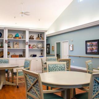 A cozy interior room with tables, chairs, and a decorated bookshelf.